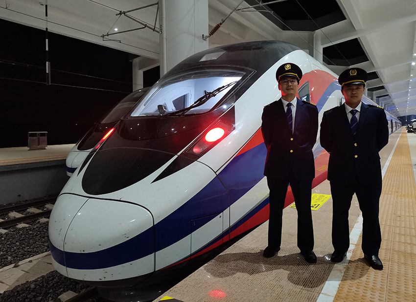 劉銀能（右一）與中國(guó)師父鄔俊鴻在動(dòng)車(chē)組前合影。受訪者供圖